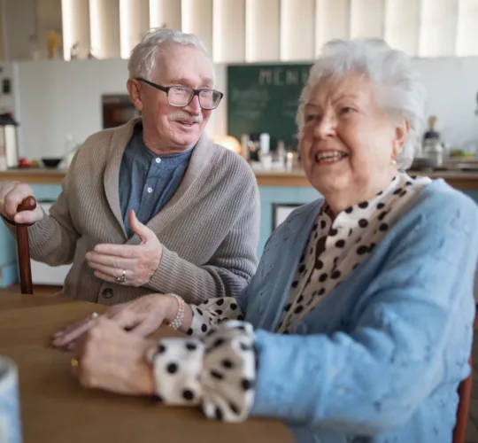 A smiling elderly woman and man enjoying breakfast in nursing home care center.